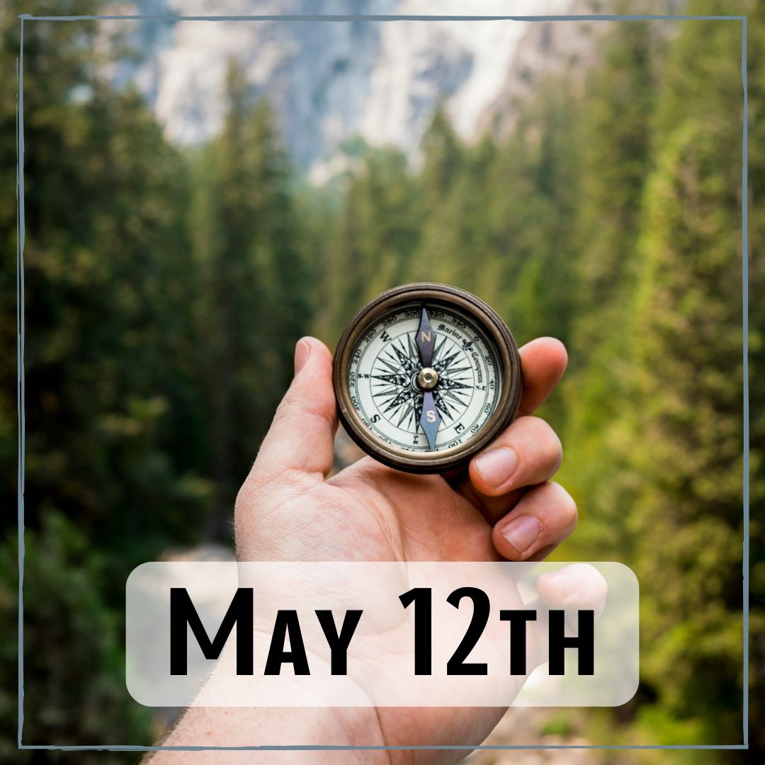 May 12th - a hand holding a compass in the forest