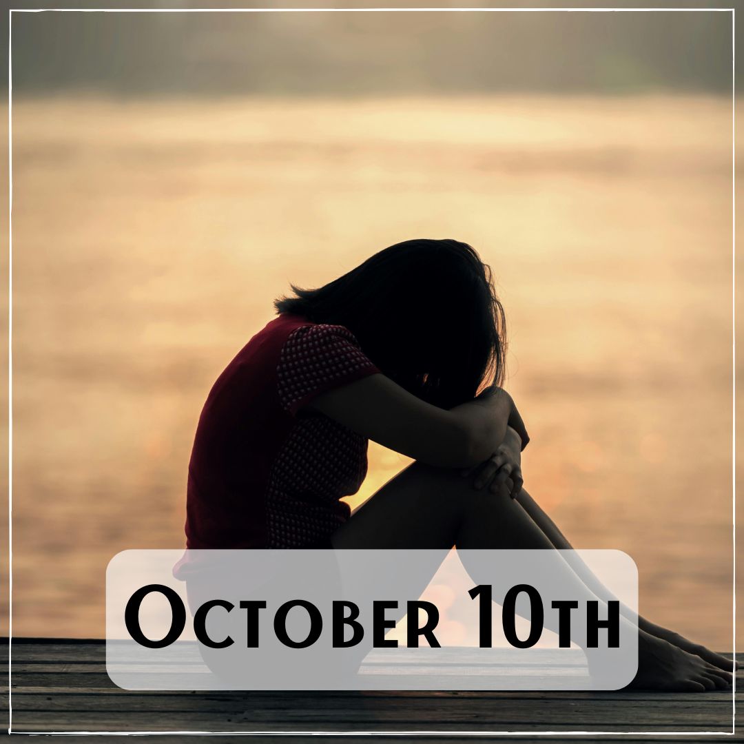 October 10th - a person sitting next to a lake at sunrise with the head resting on their knees