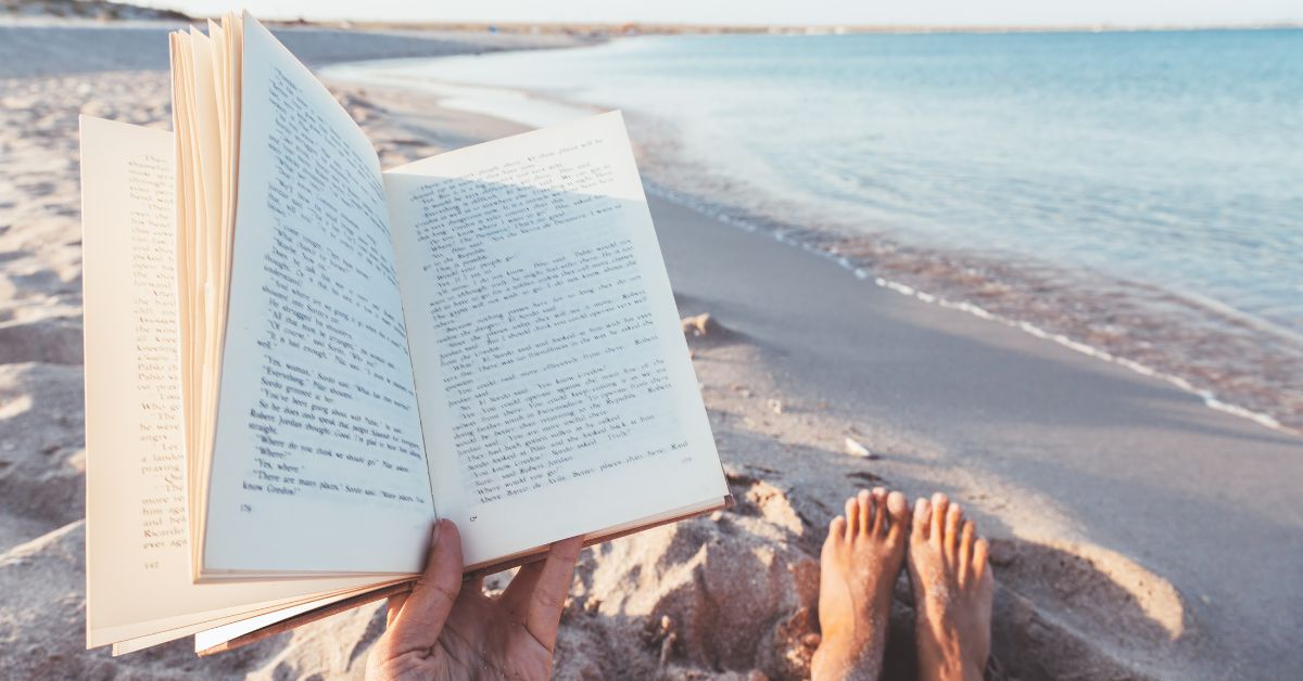 a person reading a book on the beach