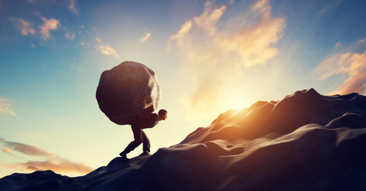 image: a person carrying a boulder up a hillside