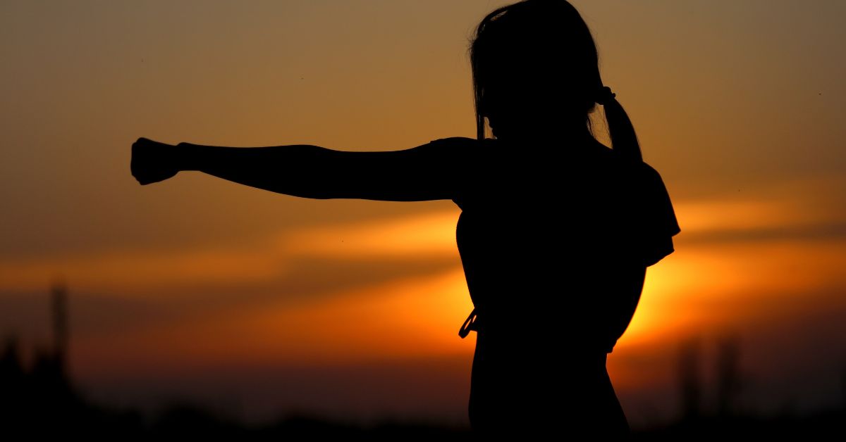 a person in a punching stance, with the sunrise behind them