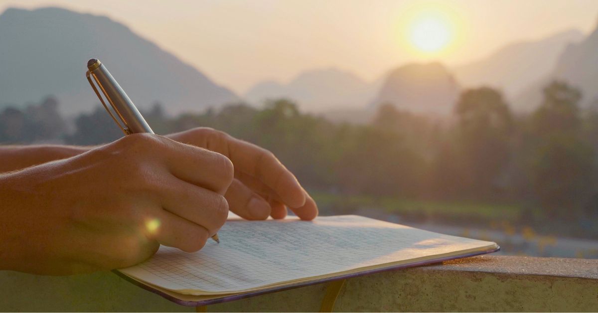 Image: someone writing a letter with a mountain backdrop