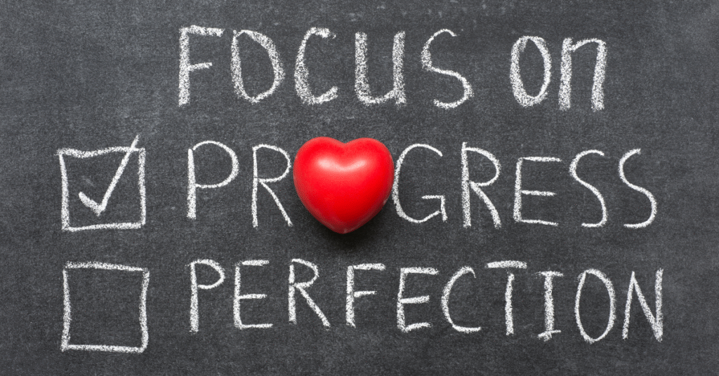 progress not perfection written on a chalkboard with a heart replacing the letter "O"