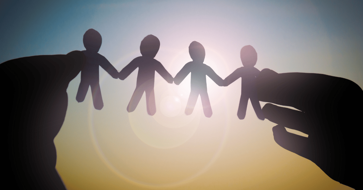 A person's hands holding a paper mache of people holding hands