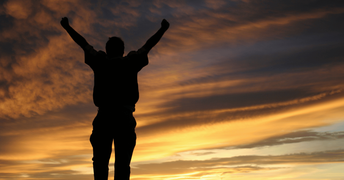 A [person with their arms up expressing their freedom to the sky