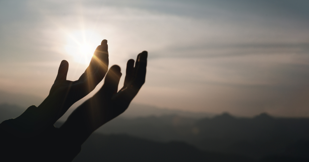Two hands open and outstretched in front of a bleak sky