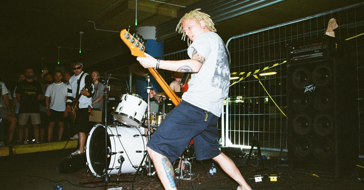 An energetic musician playing guitar in a dimly lit, grunge venue